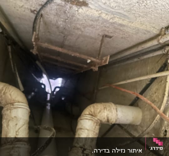 צינורות מתכת חלודים בתקרה עם נזילות מים